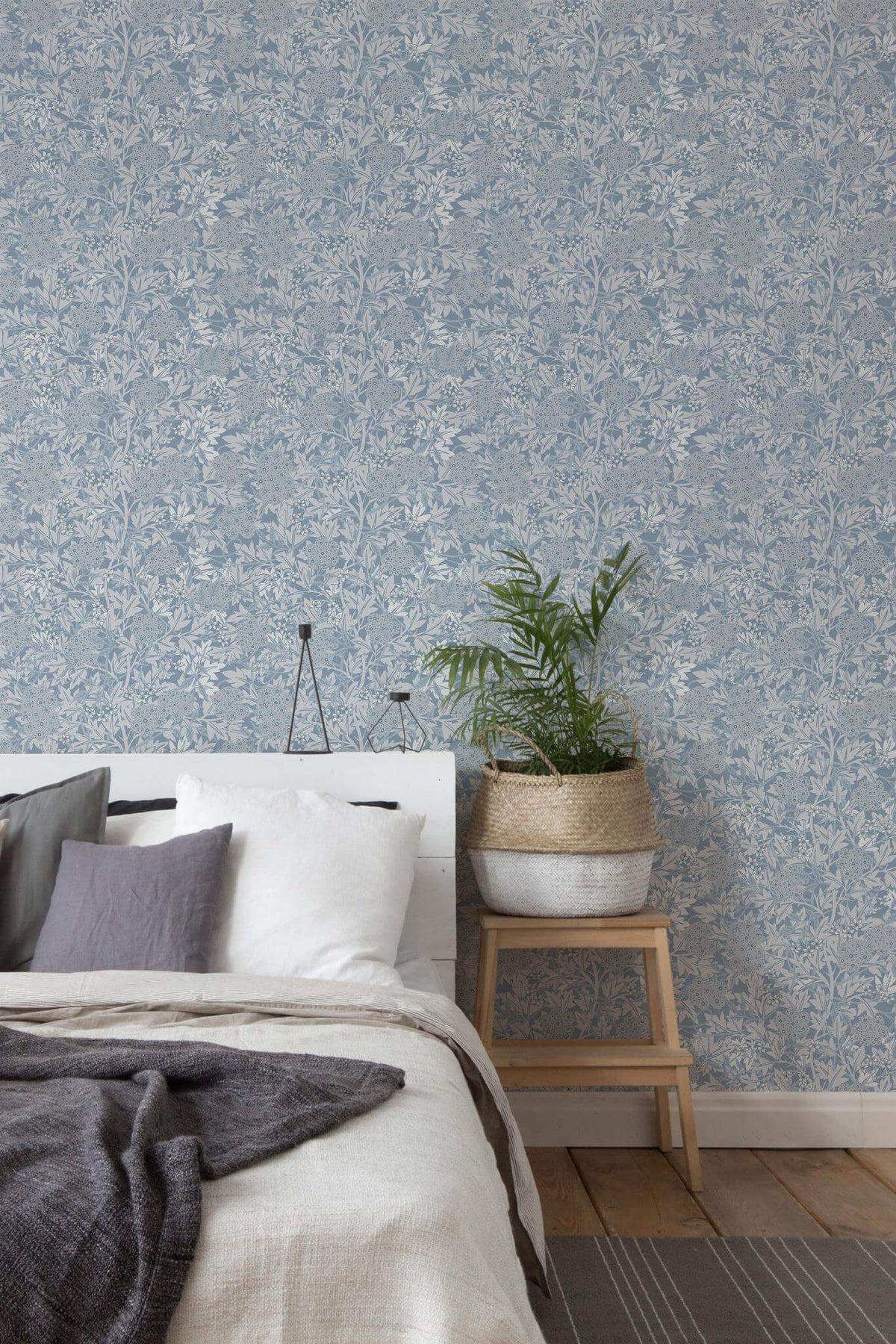 Quarto de estilo escandinavo com parede revestida a papel de parede de folhagem vintage em azul e cinzento